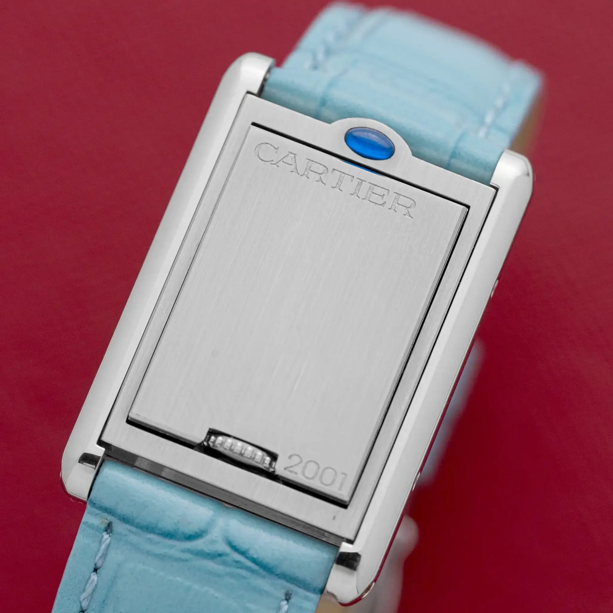 Reverse of the Cartier Tank Basculante 2386 swivel case engraved "CARTIER" and "2001," on a red background.