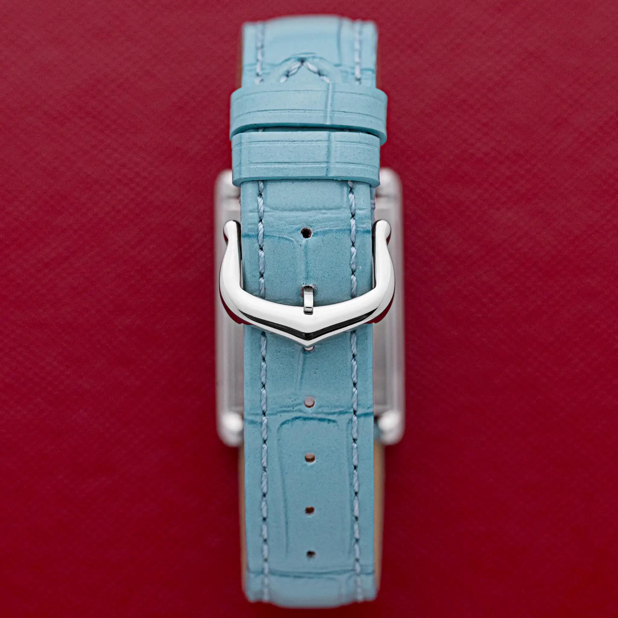 Inside of the Cartier Tank Basculante swivel cradle showing clasp and leather strap, on a red background.